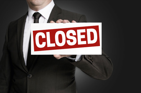 Closed sign held by businessman.の写真素材