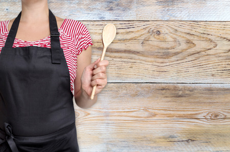 concept template cook holding wooden spoon with wooden background.の写真素材