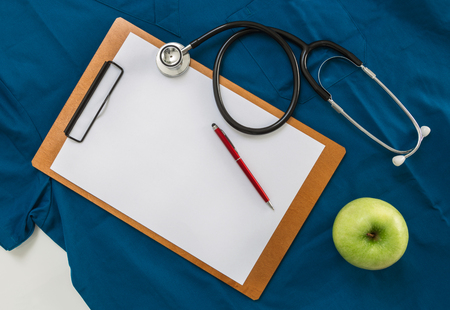 Clipboard, apple and stethoscope on hospital uniform.の写真素材