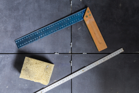 Tiles concept tool, angle, ruler, sponge on tiles top view.