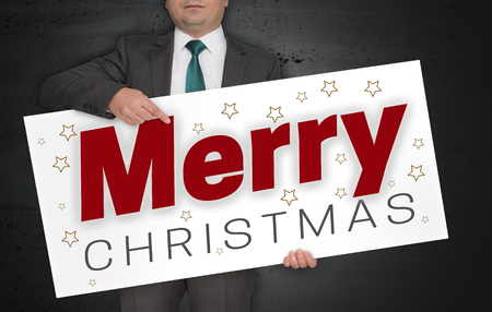 Merry Christmas poster is held by businessman.の写真素材