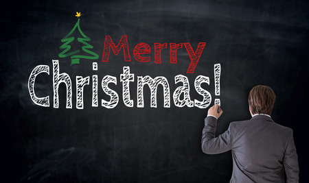 Businessman writes Merry Christmas on blackboard Concept.の写真素材