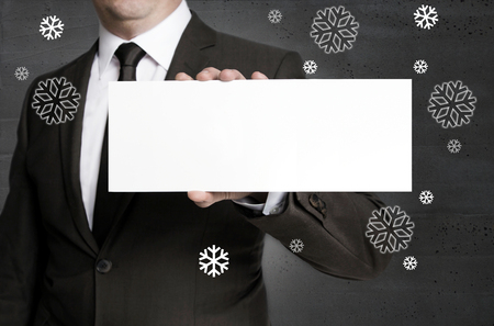 Blank signboard and snowflakes is held by businessman.の写真素材
