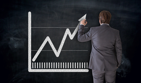 Businessman paints chart on blackboard concept.の写真素材