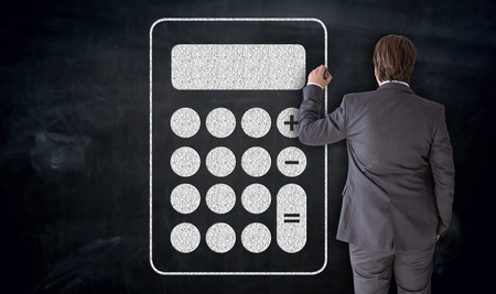 Businessman paints calculator icon on blackboard concept.の写真素材