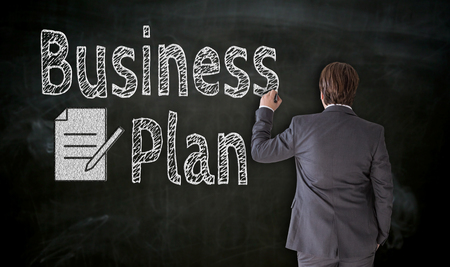 Businessman paints business plan on blackboard concept.の写真素材