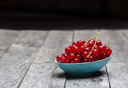 Currants in bowl on wooden background.