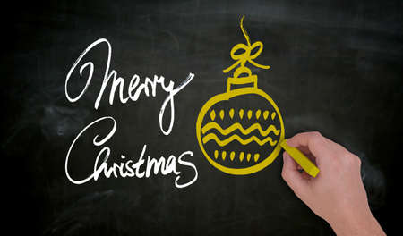 Merry Christmas is painted by hand in chalk on blackboard.の写真素材