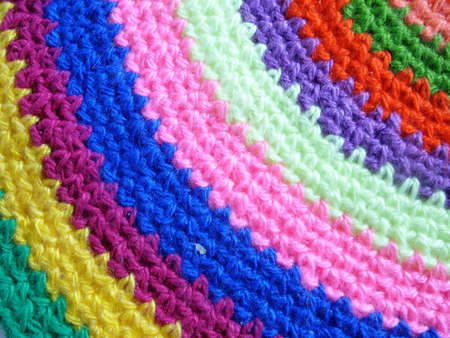 Fragment of a knitted round rug from multi-colored strips