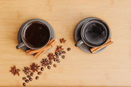 Cup of coffee with coffee beans on the background of the table with cinnamon and star anise.の写真素材