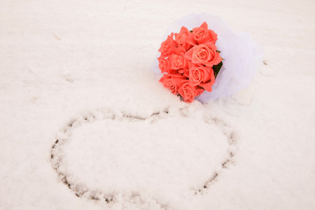 Winter wedding bouquet of pink roses, pine cones and christmas tree branches on snow, copy spaceの写真素材