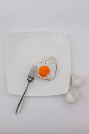 Breakfast Heart shaped egg on a white plate. Breakfast concept