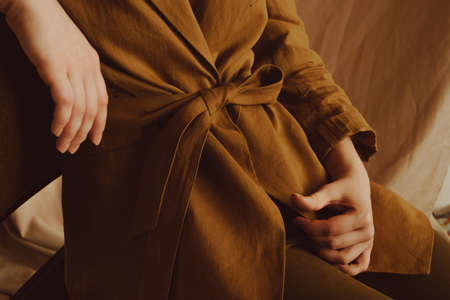 A young woman in a brown jacket sits on a chair.の写真素材