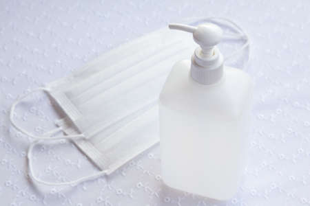 Alcohol gel hand sanitizer in pump bottle and face mask on lace table cloth.の写真素材