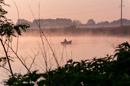 Fisherman in boat on the lake at sunrise in the morning.の写真素材