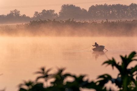 Fisherman in boat on the lake at sunrise, Thailand.の写真素材