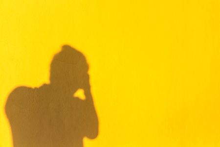 Shadow man take a photograph on the yellow wallの写真素材