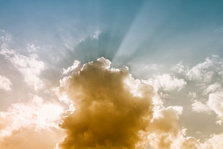 Sun beamlight behind  orange clouds with blue sky