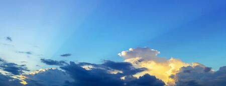 sun rays light and orange light in evening sky with dim cloudsの写真素材