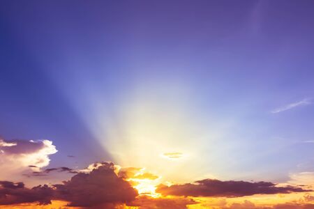 orange and yellow sunset light with red orange light in clouds in purple blue sky
