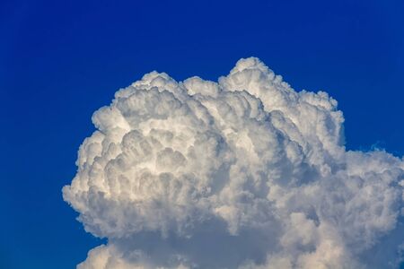 Fluffy dim clouds in deep blue skyの写真素材