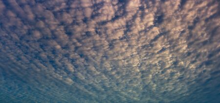 last light of day on cloud streak in overcast blue skyの写真素材
