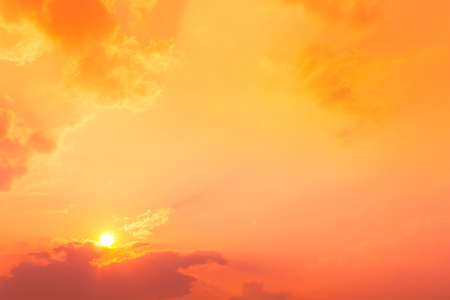 sundown with orange and red color light in sky and cloudsの写真素材