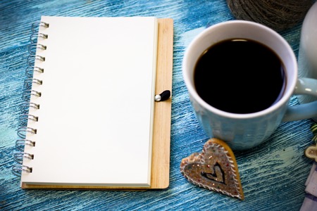 Festive still life with blue cup of freshly brewed coffee, biscuits, open notebook on turquoise wooden table, blue backgroundの写真素材