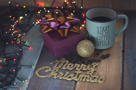 Gift box and cup of coffee, gold inscription on the tableの写真素材