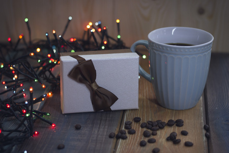Gift box with bow, blue cup, lights, on Christmas tableの写真素材