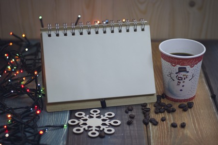Notepad and glass on a wooden Christmas table and a snowflakeの写真素材