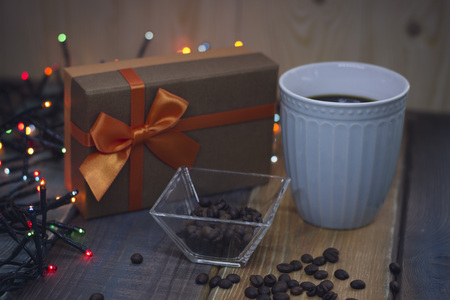A brown gift box with an orange bow and blue cup on the tableの写真素材