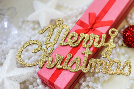 Merry christmas inscription, red gift box and christmas tree decorations