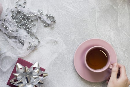 Hand holding a cup, a gift box, a ribbon, beadsの写真素材