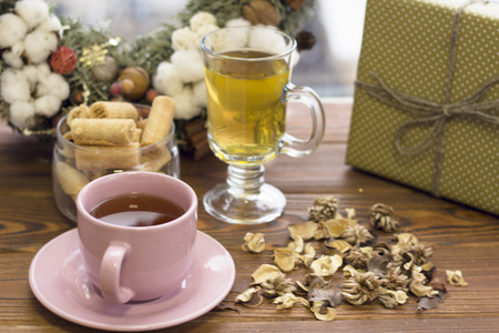 Pink tea cup with saucer, glass tea cup, cookies, a gift box and a Christmas wreathの写真素材