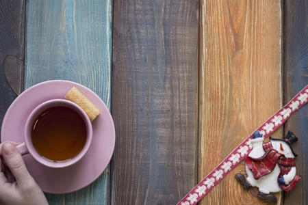 Hand holding tea cup, toy snowman, patterned christmas ribbonの写真素材