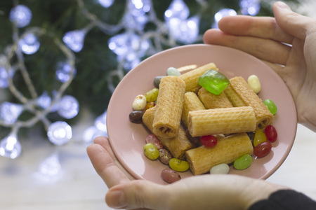 Hands holding a festive saucer with cookies and candiesの写真素材