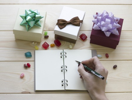 Christmas still life with gift boxes and a hand writing in a notebook notebook.の写真素材