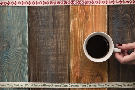 Christmas wooden background with hand holding a cup