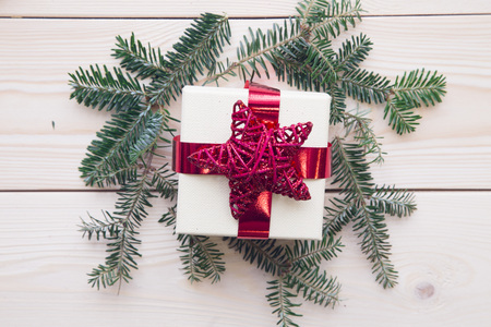 A gift box with fir tree branches on a light wooden backgroundの写真素材