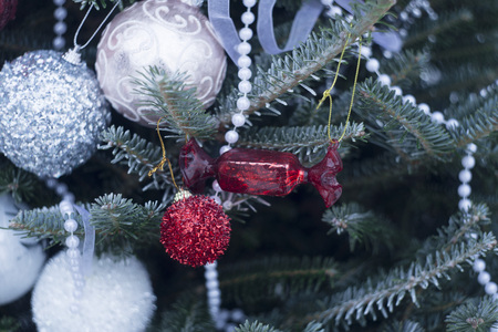 A festive mood with beautifully decorated Christas tree. White, Silver and red baubles and beads on fir tree branches covered with frost. Close up.の写真素材
