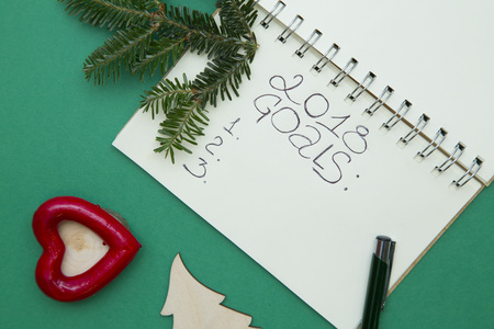 Writing New Year goals. Green Christmas or New Year background with a notebook,a spruce branch and Christmas tree toys. Space for your text or image. Top view.の写真素材