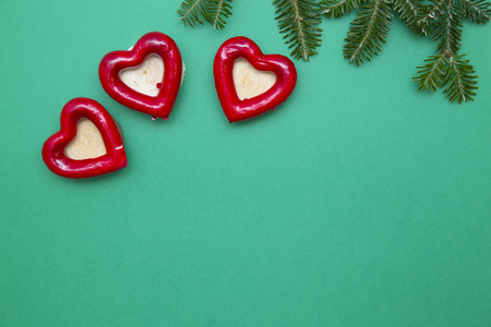 New Year composition with tree red hearts with wooden centers and natural spruce branch. Green one-color Christmas or New Year background. Space for your text or image. Top view.の写真素材