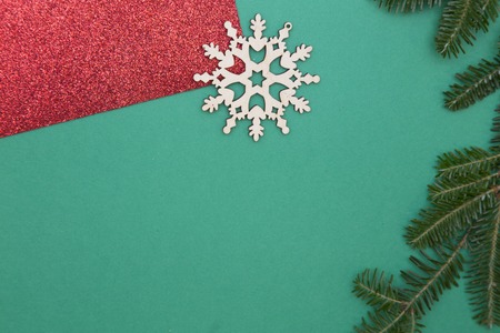 Green one-color Christmas or New Year background with red gleaming wraping paper, wooden snowflake and a natural spruce branch. Space for your text or image. Top view.の写真素材