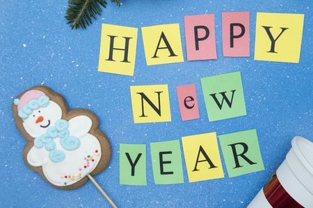 Happy New Year inscription a gingerbread snowman on a blue one color background with little white spots. Top view. Close upの写真素材