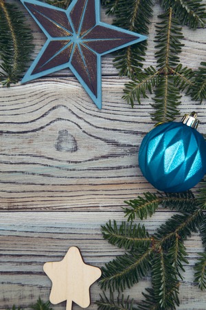 Light wooden shabby background with spruce branches and blue Christmas-tree ornaments. Space for your text or product display. Top view. Close upの写真素材