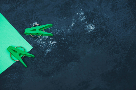 Tidying up a house, office or hotel with green cleaning rag and green plastic clothes pegs. Bright composition of cleaning tools, dark concrete background. Space for your product displayの写真素材