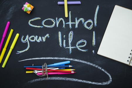 Motivation words. Control your life inscription on a blackboard written with colored chalks, colored pencils, markers and chalks and an eraser on a blackboardの写真素材
