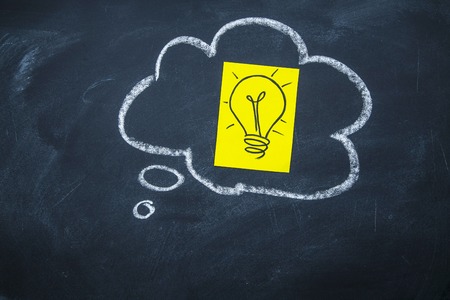 New idea. Think or speech bubble drawn with a chalk on a blackboard with a light bulb image insideの写真素材