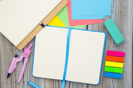 Exams preparation with blank notebooks, a pair of compasses, sticker notes and eraser on a wooden table. Space for your text or product display.の写真素材